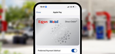 A smartphone screen with Apple Pay open. The visible card is Exxon Mobil Direct Debit+. It is set as the preferred payment method