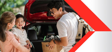 A man, woman and baby are loading the back of their SUV.