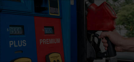 A person's arm is shown hanging up the gas nozzle at an Exxon gas pump.
