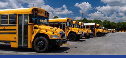 Several school buses lined up in a parking lot with text: Municipalities