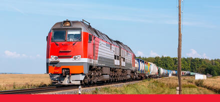 A red train driving down a train track with text: Rail