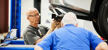 Two men working on the hitch of a car