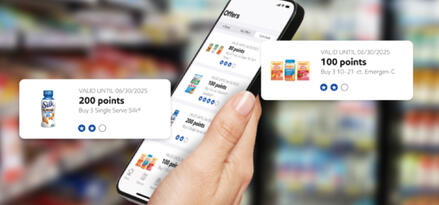 A hand holding a phone with Club Card offers on the screen. There are example items worth 100 and 200 points.