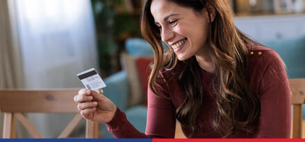 A woman smiling and looking at a gift card