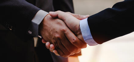 A close-up of two businessmen handshaking in suits.