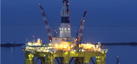 An offshore drilling site at nigh with many lights shining.