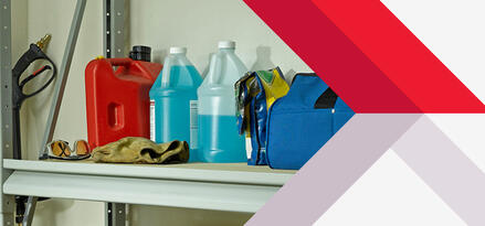 A red gasoline container, two bottles of wiper fluid, and safety items, including plastic goggles and gloves, on a garage storage shelf.