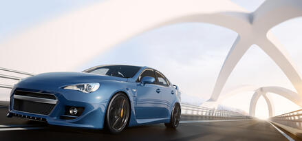 A blue car zooming down a futuristic-looking bridge.