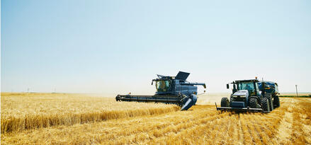 combine harvester and a tractor working in a wheat field.