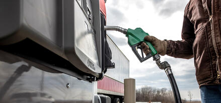 Trucker wearing gloves pumps diesel fuel.