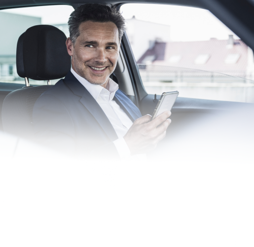 Man sitting in parked car holding his mobile phone