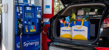 Car at a gas station with Walmart+ grocery bags in the trunk