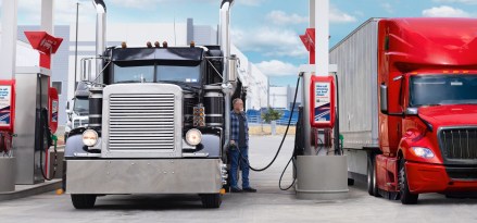 A black semi-truck filling up at a Mobil Diesel Efficient pump