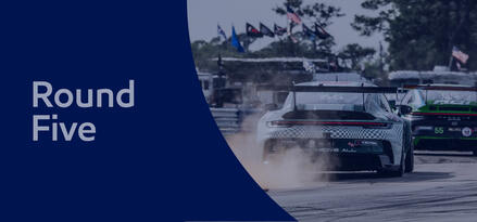 Close up from behind of two race cars, one right behind the other, with text: Round Five. Blue sheer overlay on whole image.